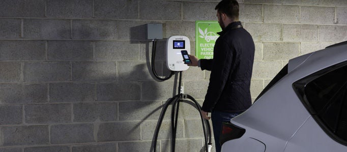 Man charging electric vehicle in parking garage