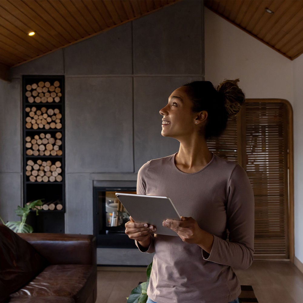 Woman on tablet, controlling lights in home.
