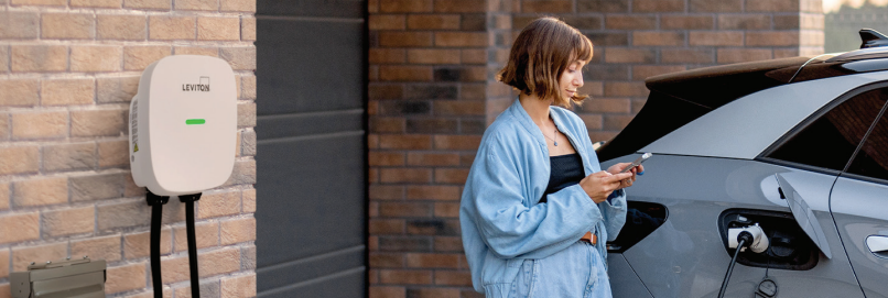 Woman using Phone while charging EV Vehicle