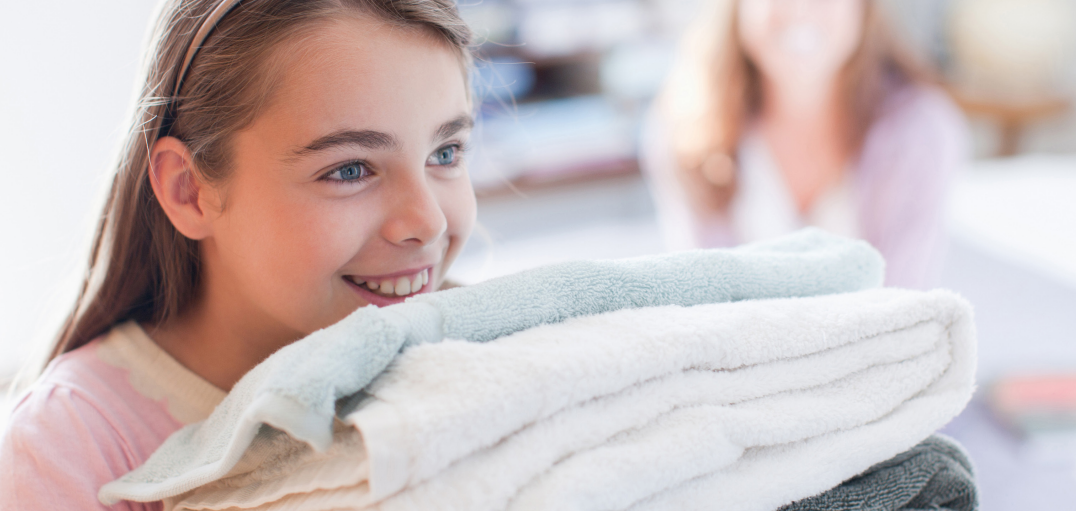 Little girl holding folded laundry